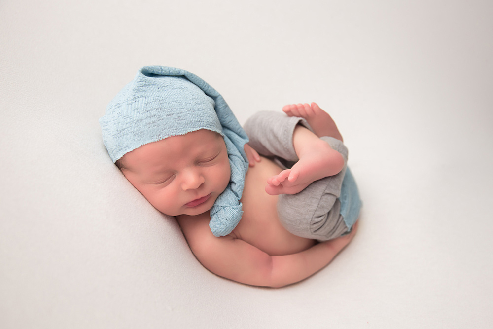 adorable baby boy wearing knit cap and crossing legs for joanna andres newborn photo shoot