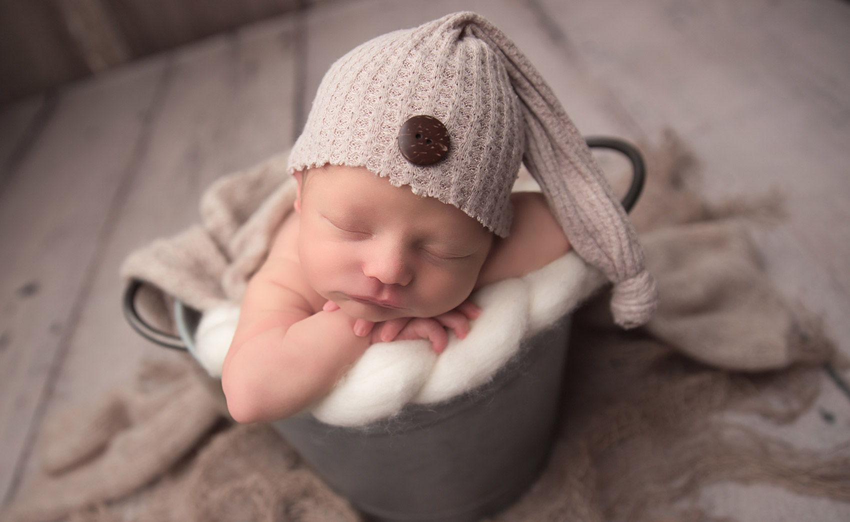 cute little newborn boy posing for photo shoot by joanna andres and wearing a knit cap